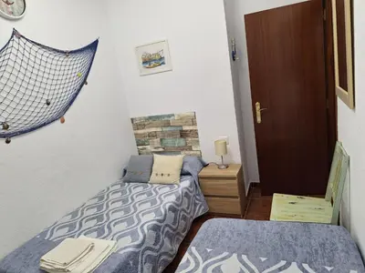 a small room with two beds and a door at El Deseo in Novo Sancti Petri