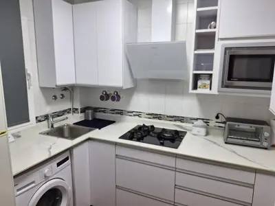 a white kitchen with a stove top oven next to a sink at El Deseo in Novo Sancti Petri