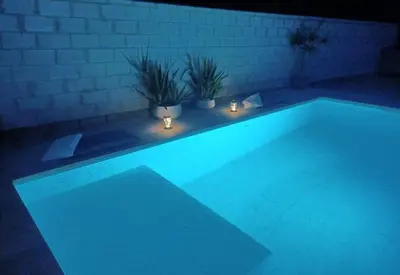 a swimming pool lit up at night with lights at Habitación acogedora y sencilla in El Puerto de Santa María