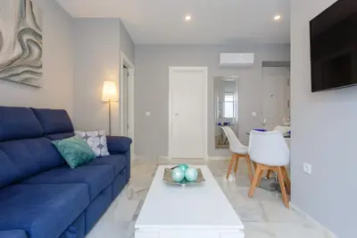 a living room with a blue couch and a table at Apartamento Cádiz Mirador by Isa in Cádiz