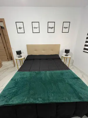 a bedroom with a bed with a green blanket on it at Mrati - Playa in Puerto Real