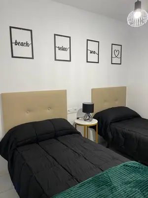 a bedroom with two beds and pictures on the wall at Mrati - Playa in Puerto Real