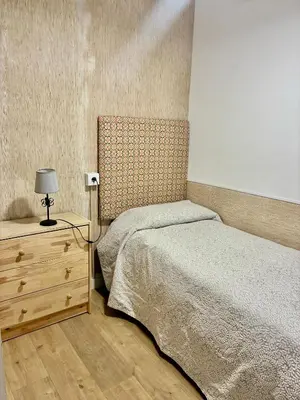 a bedroom with a bed and a dresser with a lamp at Apartamento Gallo Azul in Jerez de la Frontera