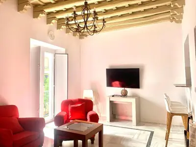 a living room with a red chair and a tv at Apartamento Gallo Azul in Jerez de la Frontera