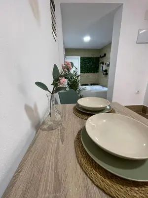 a table with two plates and a vase with flowers on it at Estudio BF jacuzzi jerez in Jerez de la Frontera