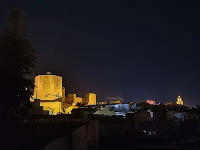 a city lit up at night with a building at L' Alcoba Rooftop in Sanlúcar de Barrameda