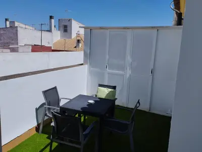 a table and chairs on a balcony with a blue light at L' Alcoba Rooftop in Sanlúcar de Barrameda