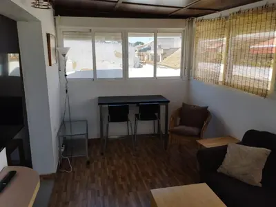 a living room with a table and chairs and a window at L' Alcoba Rooftop in Sanlúcar de Barrameda