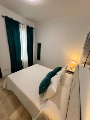 a bedroom with a white bed with a blue pillow at CARPE DIEM in Jerez de la Frontera