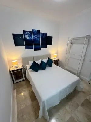 a bedroom with a white bed with blue pillows at CARPE DIEM in Jerez de la Frontera