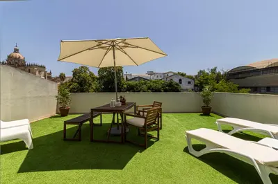 a patio with a table and chairs and an umbrella at Allo Apartments Arroyo Ático Parking Centro 1 Habitación in Jerez de la Frontera