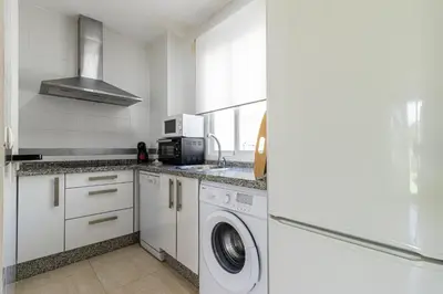 a white kitchen with a washer and dryer in it at Allo Apartments Arroyo Ático Parking Centro 1 Habitación in Jerez de la Frontera