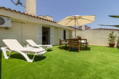 a patio with lawn chairs and an umbrella at Allo Apartments Arroyo Ático Parking Centro 1 Habitación in Jerez de la Frontera