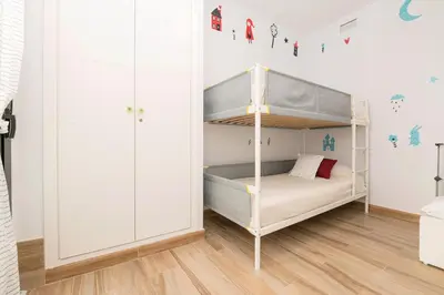 a white bedroom with a bed and a desk at Loving Rota in Rota