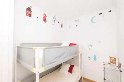 a childs bedroom with a bunk bed and white cabinets at Loving Rota in Rota