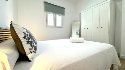 a bedroom with a large white bed and a mirror at SIBS Sanlúcar Guadalquivir I - TERRAZA in Sanlúcar de Barrameda