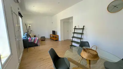 a living room with a glass table and chairs and a clock at SIBS Sanlúcar Guadalquivir I - TERRAZA in Sanlúcar de Barrameda