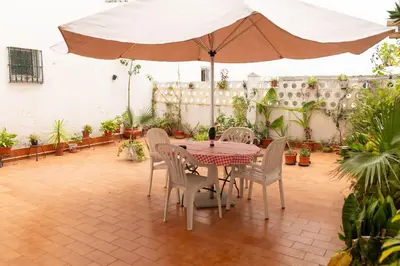 a patio with a table and chairs and an umbrella at El Patio de la Viña by Gades Gestión in Cádiz