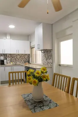 a vase with yellow flowers on a table in a kitchen at El Patio de la Viña by Gades Gestión in Cádiz