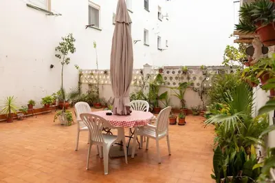 a patio with a table and chairs and an umbrella at El Patio de la Viña by Gades Gestión in Cádiz