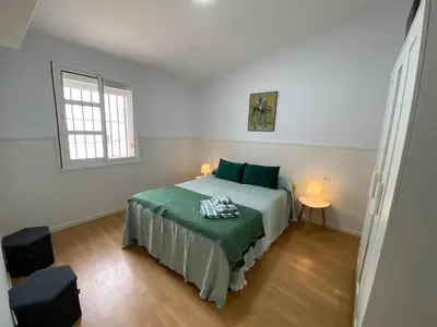 a bedroom with a bed with green sheets and a window at TU ESCONDITE in Jerez de la Frontera