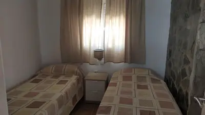 two beds in a small room with a window at Casita café in Chiclana de la Frontera