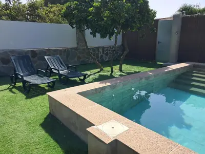 two chairs and a swimming pool in a yard at Casita café in Chiclana de la Frontera