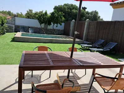 a wooden table with chairs and an umbrella in a backyard at Casita café in Chiclana de la Frontera