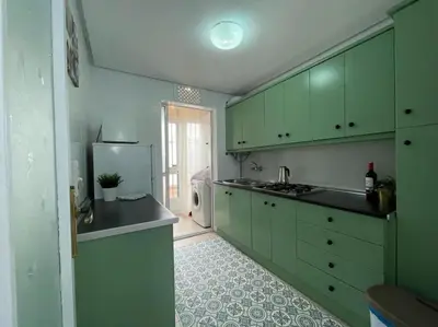 a kitchen with green cabinets and a refrigerator at Apartamento ZIUREV IV in Sanlúcar de Barrameda