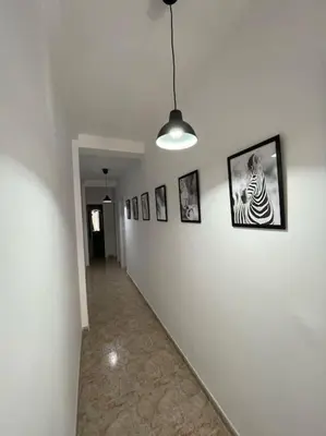 a hallway with pictures on a white wall at Apartamento ZIUREV IV in Sanlúcar de Barrameda