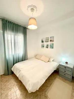 a bedroom with a white bed and a window at Apartamento ZIUREV IV in Sanlúcar de Barrameda
