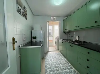 a kitchen with green cabinets and a refrigerator at Apartamento ZIUREV IV in Sanlúcar de Barrameda