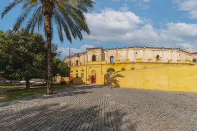 a yellow building with a palm tree in front of it at Manolete apartamento in Jerez de la Frontera
