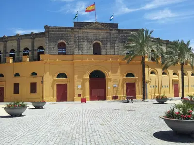 a yellow building with palm trees in front of it at Villa Marcel in Jerez de la Frontera