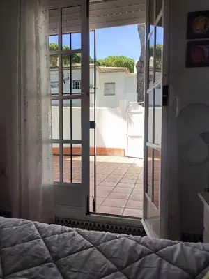 a bedroom with a bed and a view of a patio at Apartamento Pinar del Atlántico La Barrosa in Chiclana de la Frontera