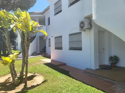 a white house with two trees in the yard at Apartamento Pinar del Atlántico La Barrosa in Chiclana de la Frontera