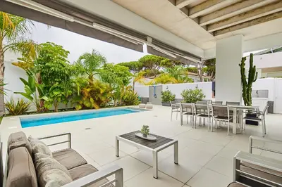 a living room with a couch and a table and a pool at Villa caracolillo PLAYA Chiclana in Chiclana de la Frontera