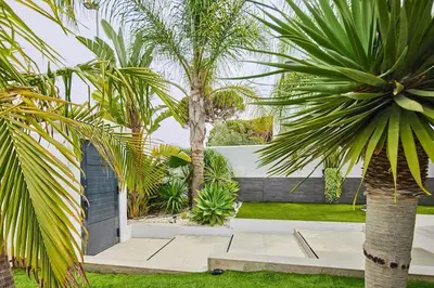 a courtyard with palm trees and a house at Villa caracolillo PLAYA Chiclana in Chiclana de la Frontera