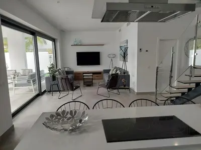 a living room with a table and chairs and a television at VILLA caracolillo MAR in Chiclana de la Frontera