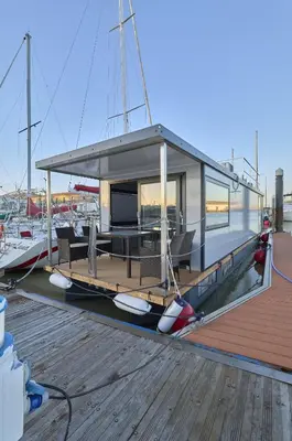a boat with a cabin sitting on a dock at The Boathouse Company - Casa flotante experience - Real Club Náutico, El Puerto de Santa María in El Puerto de Santa María
