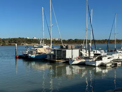 a group of boats docked at a dock in the water at The Boathouse Company - Casa flotante experience - Real Club Náutico, El Puerto de Santa María in El Puerto de Santa María
