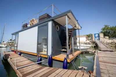 a small boat is docked at a dock at The Boathouse Company - Casa flotante experience - Real Club Náutico, El Puerto de Santa María in El Puerto de Santa María