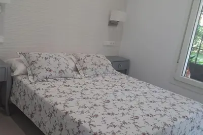 a bed with a floral comforter and pillows in a bedroom at Chalet en Roche - Amplio jardín in Roche