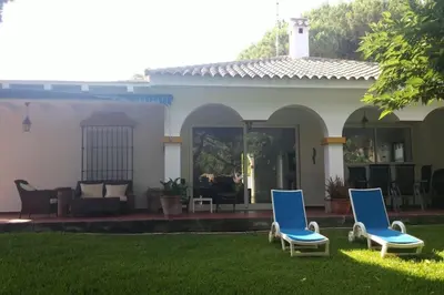 two blue chairs in front of a house at Chalet en Roche - Amplio jardín in Roche