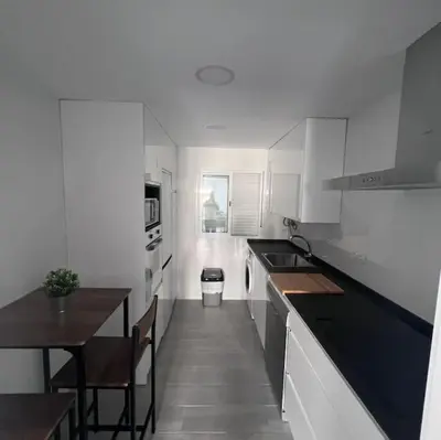 a kitchen with white cabinets and a table and a dining room at piso en pleno centro in San Fernando