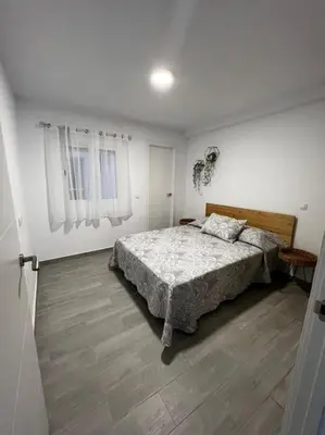 a white bedroom with a bed and a wooden floor at piso en pleno centro in San Fernando