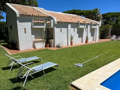 a house with a yard with a pool and two chairs at Villa America in Roche