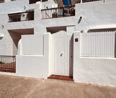 a white building with white gates on the side of it at Apartamento Empul Costa Sancti Petri in Chiclana de la Frontera