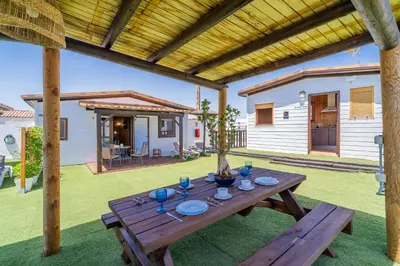 a wooden picnic table in a yard with a house at El Paraíso Perdido in Conil de la Frontera