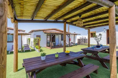 a patio with two wooden picnic tables in a yard at El Paraíso Perdido in Conil de la Frontera
